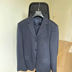 Mörkblå kostym – Mediterranea, Made in Italy (stl 50) - Stilren mörkblå kostym från Mediterranea, Made in Italy. Tillverkad i en bekväm mix av ull, polyester och elastan vilket ger en modern passform och skön komfort.  Storlek: 50  Färg: Mörkblå  Skick: Ny, utan tagg därav priset. 