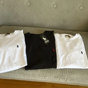 3-pack Polo Ralph Lauren t-shirts - Säljer ett 3-pack klassiska t-shirts från Polo Ralph Lauren i storlek S. Två vita och en svart, alla med den ikoniska broderade loggan på bröstet. T-shirtsen är kortärmade och gjorda i mjuk bomull med rund hals. Perfekt för dig som gillar stilrena och tidlösa plagg. 1st 400kr, 2st 700, 3st 1000