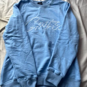 Blå oversized tröja från Corteiz med tryck - Snygg ljusblå crewneck från Crtz med vitt grafiskt tryck framtill. Tröjan har rund hals, ribbade muddar och är tillverkad i mjuk bomull. Storlek S men passar M. Aldrig använd.