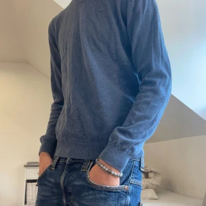 Blå v-neck tröja från Hamton republic - Snygg blå v-ringad tröja från Hamton republic, perfekt för dig som gillar stilrena och klassiska plagg. Tröjan har ribbade muddar vid ärmslut och nederkant, samt diskret Hamton republic-logga på bröstet. Storlek S. Skriv vi minsta fundering