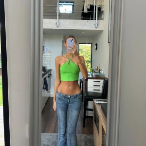 Grön croppad halterneck topp - Säljer en ljusgrön croppad halterneck topp med ribbad struktur och snygg nyckelhålsdetalj framtill. Toppen har smala band som korsas och knyts i nacken, samt öppen rygg. Perfekt för varma dagar och sommarvibes.