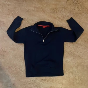 Mörkblå half zip tröja från RYVLS - Mörkblå långärmad tröja från RYVLS med half zip-dragkedja framtill. Tröjan har en hög krage och är tillverkad i mjukt material som känns skönt mot huden. Tröjan är i storlek 146-152. Pris kan diskuteras och skriv vid funderingar!