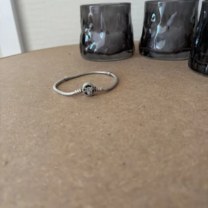 Pandora silverarmband med blomma - Snyggt armband från Pandora i äkta silver. Är i mycket gott skick, använt ca 5 gånger. Har tyvärr inte boxen kvar Perfekt för dig som gillar detaljer och vill ha något unikt på handleden. Kan vara villig att ändra priset vid snabb affär. 