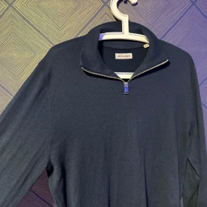 Mörkblå half zip tröja Jack & Jones - Mörkblå långärmad tröja från Jack & Jones med stilren half zip-dragkedja vid kragen. Tröjan är i mjukt material och har en klassisk passform som funkar till många olika looks. Perfekt för dig som gillar enkel och clean stil.