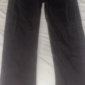 Svarta raka jeans från 157 - Svarta jeans från 157 med klassisk femficksmodell och raka ben. Jeansen har en enkel design med silverfärgade nitar och knapp, samt normal midja. Perfekta för dig som gillar en clean och tidlös look. Aldrig använda. 