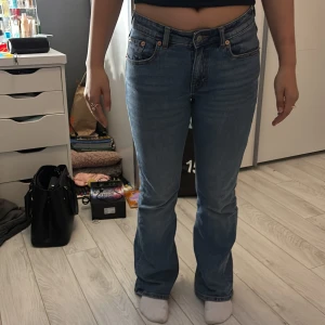 Blå bootcut jeans från 157, stl S - Säljer ett par klassiska blå jeans från 157 i storlek S med kort benlängd. Modellen har bootcut-ben, normal passform och fem fickor. Jeansen är i mjukt denimtyg och har snygga detaljer med kopparfärgade nitar och knappar.