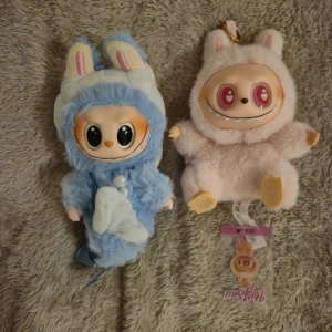 Söt lafufus med nyckelring  - Unik och gullig plånbok i mjuk plysch med kaninöron och stort ansikte. Plånboken är beige med rosa detaljer och har ett praktiskt fäste för att hänga på väskan eller nyckelringen. Perfekt accessoar för dig som gillar kawaii-stil. Säljer 2st för 450kr