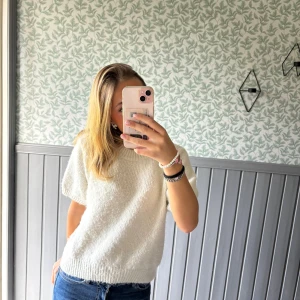 Vit stickad kortärmad tröja - Mysig vit stickad tröja med korta ärmar och rund hals. Det är en l men passformen är som s