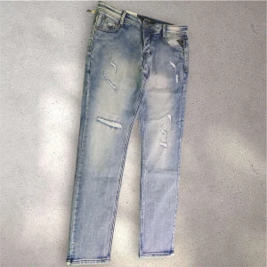 Replay jeans - Säljer ett par Replay Hyperflex jeans i ljusblå tvätt med slitningar och distressed detaljer framtill. Jeansen har klassisk femficksdesign, normal passform och stretchigt material för extra komfort. Perfekta för en avslappnad och trendig look.