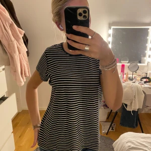 Svartvit randig t-shirt i bomull - En svart t-shirt med vita horisontella ränder och rund halsringning. Klassisk passform och korta ärmar, perfekt till jeans eller shorts. Gjord i mjuk bomull som är skön mot huden. Enkel och stilren design som funkar året runt.