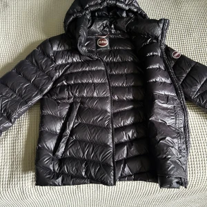 Svart Colmar pufferjacka med huva - Säljer en svart pufferjacka från Colmar med huva och dragkedja. Perfekt för kalla dagar och riktigt snygg till streetwear-stilen. Hör avvdig vid frågor och funderingar!