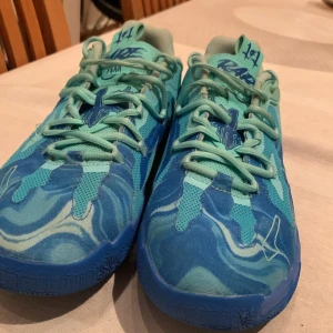 Puma rare basket skor  - Unika Puma MB.01 Rare sneakers i blått och turkost med coolt vågmönster och texten 'RARE' under sulan. Skorna har snörning, meshpaneler och detaljer med M.E.L.O. på hälen. Perfekta för dig som vill sticka ut med färg och stil.