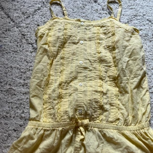 Gult korsettagtigt linne med spets från Lindex -  gul korsettaktigt linne från Lindex med smala axelband och dekorativa spetsdetaljer.