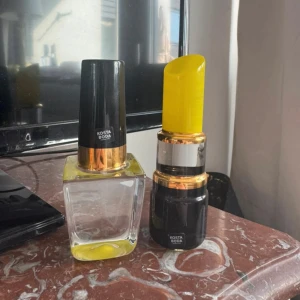 Kosta Boda sminkdekor i glas - Två handmålade dekorationsfigurer i glas från Kosta Boda, formade som ett nagellack och ett läppstift. Nagellacket har svart och guld lock med klar och gul botten, läppstiftet har gul topp och svart, guld och silver detaljer. Perfekt som cool inredning för sminkälskare. Original pris - 1400kr. Säljer för 900kr