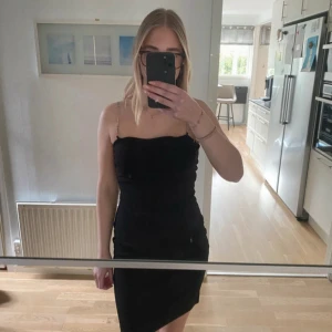 Svart kort klänning med kedjeband H&M - Supersnygg svart kort klänning från H&M med tunna kedjeband som axelband. Klänningen har en tight passform och är ärmlös, perfekt för dig som gillar en stilren och enkel look.