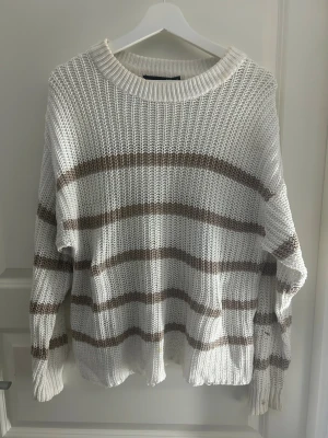 Randig stickad tröja från lager 157, M - Säljer en chill stickad tröja från lager 157 i storlek M. Den är vit med breda bruna ränder, har grov ribbad struktur och rund hals. Långärmad och loose fit, perfekt för lager på lager. Materialet är mjukt och känns som bomull. Snygg till jeans eller cargo pants. Det finns några fläckar.