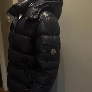 Marinblå Moncler Maya, pufferjacka med huva - Säljer denna mörkblåa moncler Maya i jätte fint skick, ändrat använd en vinter! Den är i storlek 2 så motsvarar s/m. Nypris är 18 000!! 