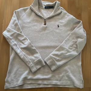  half zip tröja från Polo Ralph Lauren - Vit långärmad tröja från Polo Ralph Lauren med half zip och klassisk krage. Tröjan har det ikoniska broderade logot på bröstet och är gjord i mjuk bomull. Perfekt för dig som gillar clean och stilren look.