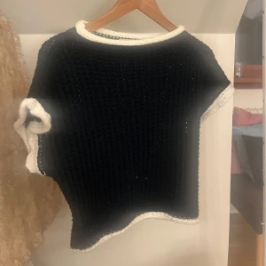 Stickad mörkblå topp från Meet Me There - Säljer en stickad topp från Meet Me There med vita kanter vid hals, ärmar och nederkant. 