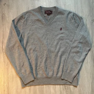 Grå v-ringad tröja Marlboro Classics - Grå v-ringad tröja från Marlboro Classics. Tröjan har ett diskret broderat logomärke på bröstet och ribbade muddar vid ärmslut och nederkant. Perfekt för dig som gillar enkel och stilren design med en klassisk touch. Det står XL men den sitter som en S!