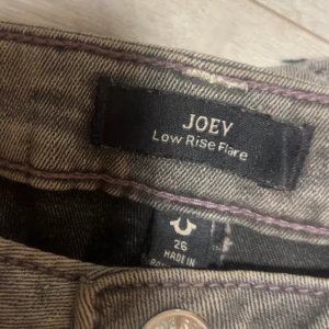 True Religion Joey Low Rise Flare Jeans - Säljer ett par gråa True Religion Joey jeans med låg midja och flare-ben som är ungefär 170 på ben längd hör av dig om du är intresserad eller har några frågor