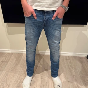  Jack & Jones jeans - Snygga blå jeans från Jack & Jones med klassisk femficksdesign och läderpatch bak i midjan. Jeansen har en smal passform och raka ben, med lätt slitna detaljer och tvättad look. Perfekt för dig som gillar en modern och stilren jeansstil.