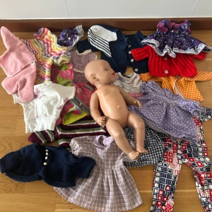 Baby born med kläder  - Säljer en söt ljuslila klänning till docka med vita prickar och puffärmar. Klänningen har rund hals och är sydd i mjukt bomullstyg. Perfekt för att klä upp din docka med lite extra stil och färg.