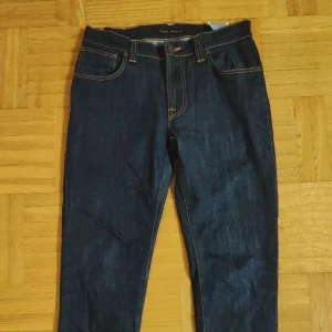 Nudie Jeans W32 - Nudie Jeans RAW mörkblå för män i storlek Waist 32 / Lenght 34. Modellen är Thin Finn och jeansen är i nyskick, inga brister. Hör av er vid intresse/funderingar. PRIS KAN DISKUTERAS!