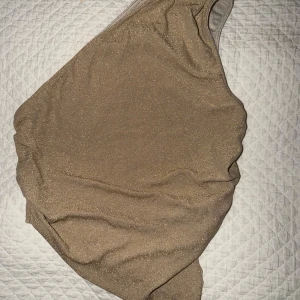 Glittrig one shoulder topp - En snygg guld glittrig one shoulder topp, perfekt när man vill vara lite lätt uppklädd. Säljer då den inte används, dessutom är den aldrig använd! 💕