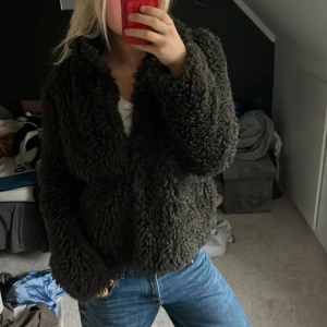 Mörkgrön teddyjacka  - Säljer en fluffig och mysig mörkgrön teddyjacka med krage. Jackan har en loose passform och är perfekt för kyliga dagar. Materialet är mjukt och ger en cool, avslappnad vibe. Passar dig som gillar streetstyle och vill ha något riktigt bekvämt.