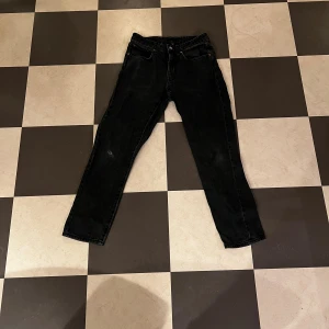 Svarta jeans från Vailent XS - Svarta jeans från Vailent i storlek XS med klassisk femficksdesign och rak passform. Jeansen har ett hål på ena benet för en edgy vibe. Materialet är robust denim och färgen är mörkt svart. Perfekt för dig som gillar en enkel men cool look.