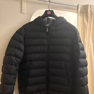 Svart Colmar pufferjacka med luva - Svart pufferjacka från Colmar med luva och två sidofickor med dubbel dragskjedja i storlek m.  Jackan är i ett riktigt bra skick.Jackan har ett ny pris på 4500kr. Vid frågor om pris eller annat skriv till mig😁