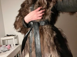 Äkta brun pälsjacka med skinn och bälte - Säljer en sjukt snygg brun pälsjacka med svarta skinnpartier och bälte i midjan. Jackan har långärmade ärmar och är fodrad med svart satin. Pälsen är fluffig och har olika bruna och beige toner som ger en cool look.
