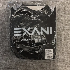 Svart underställströja från Exani - Svart underställströja och byxa från Exani i storlek 36, tillverkad i mjuk polyester som är perfekt för träning eller kalla dagar. Tröjan har rund hals och är designad för att sitta bekvämt nära kroppen. Snygg och enkel stil som funkar till lager-på-lager.