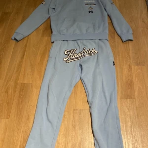 Ljusblå hoodie från Hoodrich M - Säljer en ljusblå hoodie från Hoodrich i storlek M. Hoodien har tryck och broderade detaljer på bröstet, ryggen, ärmarna och huvan. Den har en stor magficka och coola loggor som ger streetkänsla. Materialet är mjukt och skönt, perfekt för chill dagar.