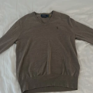Brun v-ringad tröja Polo Ralph Lauren - Snygg brun v-ringad tröja från Polo Ralph Lauren i mjuk merinoull. Hör av er om ni har några frågor 