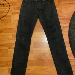 Replay Hyperflex Anbass  - Svarta Replay Hyperflex Anbass jeans med slim passform och klassisk femficksdesign. Stretchigt material för extra komfort och snygg siluett. Dragkedja i gylfen och diskreta Replay-detaljer på fickorna. Perfekt för dig som gillar stilrena och moderna jeans.