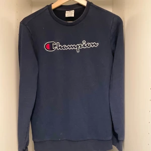  Champion sweatshirt  - Snygg mörkblå sweatshirt från Champion i storlek 13-14 X-Large. Tröjan har det klassiska Champion-logotypen broderat på bröstet och en liten logga på ärmen. Rund hals och långa ärmar, tillverkad i mjuk bomullsmix som är skön att ha på sig.