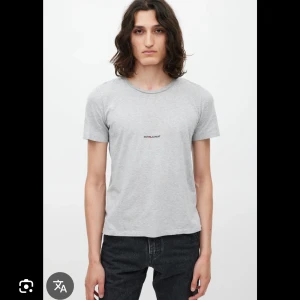 Grå Saint Laurent t-shirt - Snygg grå t-shirt från Saint Laurent med diskret logga tryckt på bröstet. Klassisk rund hals och korta ärmar. Tillverkad i mjuk bomull, perfekt för en clean och stilren look. Made in Italy. Ganska kort i storleken men i allmänt gott skick
