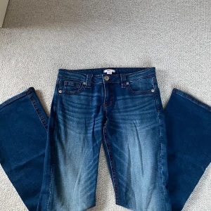 Mörkblå låg midja de jeans - Supersnygga mörkblå låg midja de jeans från Gina. Använt ett fåtal gånger och är i bra skick! De är en vinröd broderad kant och mönster på fickorna där bak! 