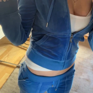 Juicy Couture Blå Sett - Säljer ett par blåa mjukisbyxor & hoodie. Byxorna har fickor framtill och en skön, avslappnad passform. Settet är som helt nya och inget är slitet eller förstört. Org pris = 2300