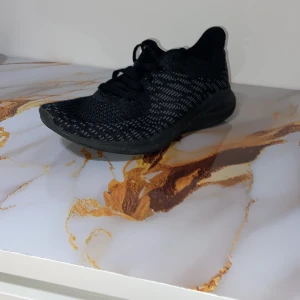 Svarta stickade sneakers med snörning - Snygga svarta sneakers med stickad ovandel och diskret mönster. Skorna har rund tå, platt sula och klassisk snörning. Perfekta för dig som gillar sportig stil och vill ha bekväma skor till vardags. Materialet är syntet och ger en lätt känsla på foten.helt nya använts en gång.