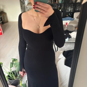 Svart ribbad långklänning BikBok - Svart långklänning från BikBok i ribbat material. Klänningen har lång ärm, figurnära passform och en snygg v-ringad urringning framtill. Perfekt för dig som gillar stilrena och trendiga plagg med en elegant touch.