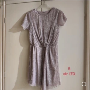 Glittrig ljuslila kortklänning - Superfin glittrig ljuslila klänning i strl 170 alltså kan passa bra från Xs S och kanske även M. 