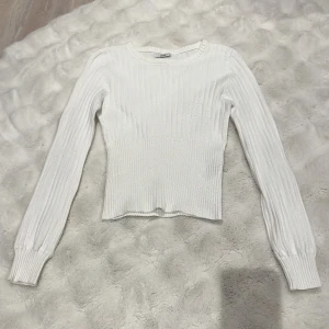 Vit ribbad långärmad tröja - Säljer en vit ribbad tröja från JDY med lång ärm och rund hals. Tröjan har en slim passform och är tillverkad i mjukt stickat material som sitter snyggt på kroppen. Perfekt att styla med jeans eller kjol för en clean look.