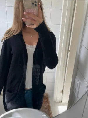 Svart stickad kofta med fickor - Lång svart kofta från Vila i storlek M men passar super för S. Använd fåtal gånger men kan upplevas lite nopprig på vissa ställen.