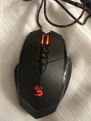 A4Tech Bloody V7 Gaming Mouse - A4Tech Bloody V7 är en avancerad gamingmus med programmerbara knappar, LED-belysning och flätad USB-kabel. Ergonomisk design för komfort vid långa spelsessioner. Musen är i gott skick med mindre spår av normalt bruk. Perfekt för gamers som söker precision och snabb respons.