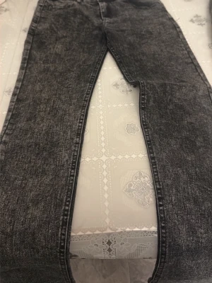 Svarta tvättade jeans med rak passform - Säljer ett par svarta acid wash jeans med rak passform. Jeansen har klassisk femficksdesign och är tillverkade i ett slitstarkt jeanstyg. Perfekta för dig som gillar en lite retro och avslappnad look.