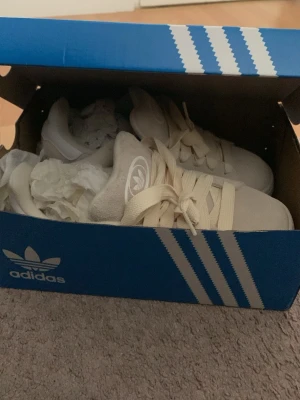Adidas Campus sneakers beige/vit - Säljer ett par Adidas Campus sneakers i beige mocka med vita detaljer och klassiska tre ränder på sidan. Skorna har platt sula i gummi med brun undersida, rund tå och snörning i ljusbeige. Perfekt för dig som gillar retrostil och snygga streetwear-vibbar. Skorna var lite för stora för mig , helt nya aldrig använda.  Storlek 38 2/3 , passar till dig som har storlek 40 i vanliga fall.  Nypris 1600 sek , säljer för 1200 aldrig använda. 