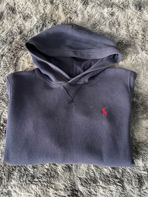 Mörkblå Ralph lauren hoodie - Jag säljer en mörkblå Ralph lauren hoodie som är perfekt för er som vill ha en skön chill tröja. Den är i storlek M(10-12)